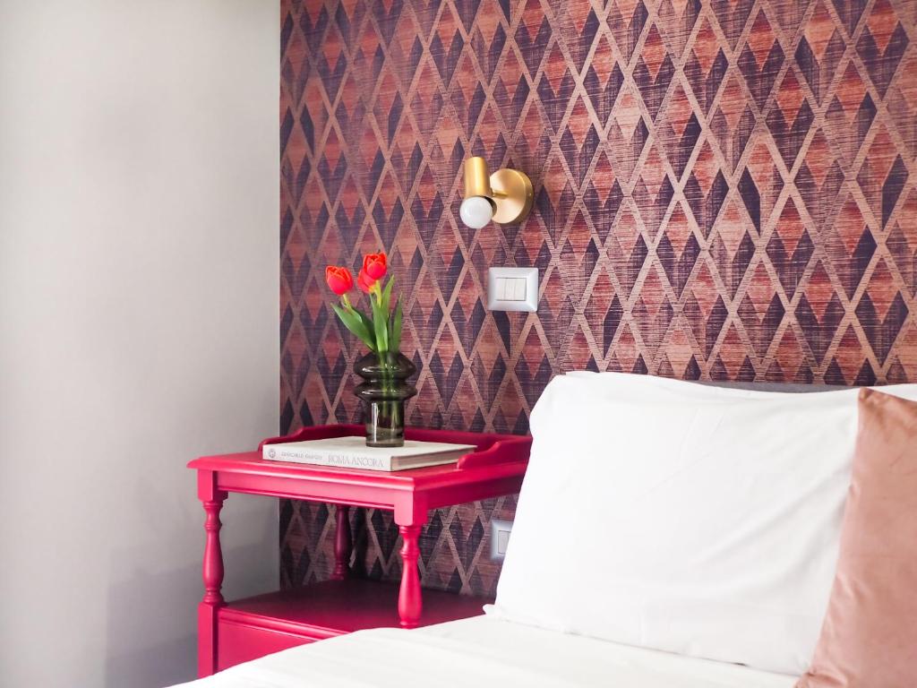 a red table with a vase of flowers on it at C'est La Vie Suites in Rome