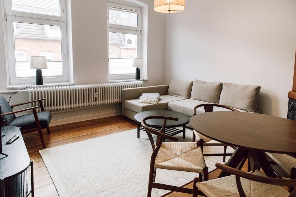 a living room with a couch and a table and chairs at Zentral und frisch eingerichtet: 2 Zi. 24h Checkin in Kiel