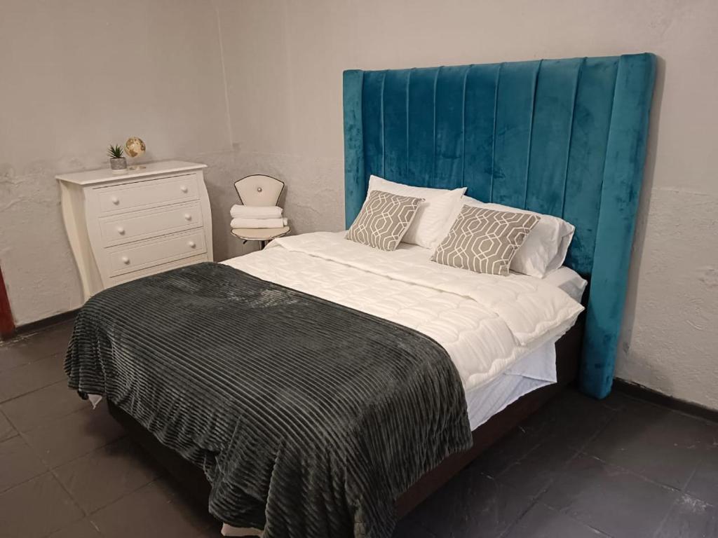 a bed with a blue headboard in a bedroom at City Dons Guest House in Vereeniging