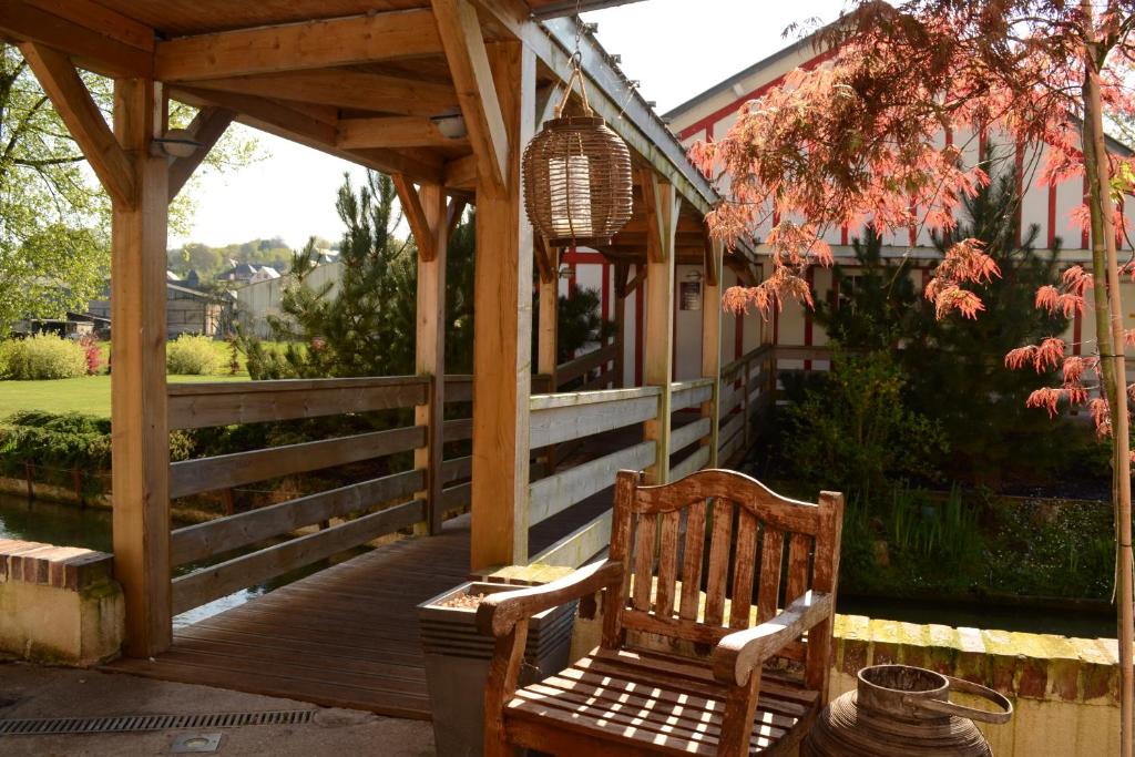 a wooden pergola with two wooden chairs on a porch at Auberge De La Durdent in Héricourt-en-Caux