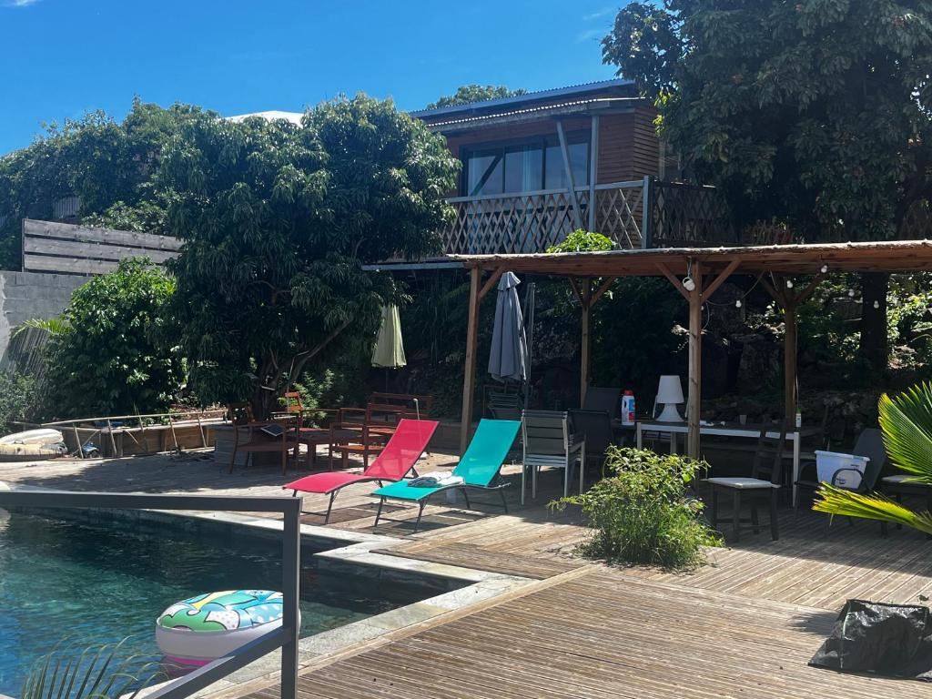 a patio with chairs and a swimming pool next to a house at bungalow vue mer au Village de l’Eperon in LʼÉperon