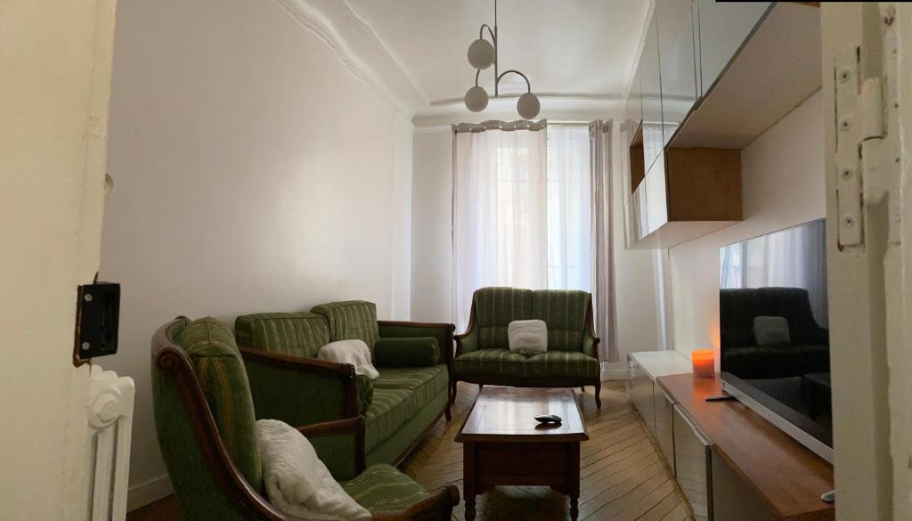 uma sala de estar com dois sofás verdes e uma mesa em Beau 3 pièces à Paris 13 em Paris