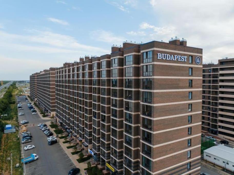 a large building with a sign on the side of it at Квартира в ЖК Будапешт 10 мин от Аэропорта и ЭКСПО in Prigorodnyy