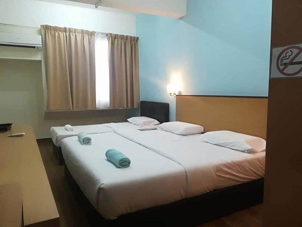 Hotel 75 Temerloh في تيميرلوه: سرير أبيض كبير في غرفة مع نافذة
