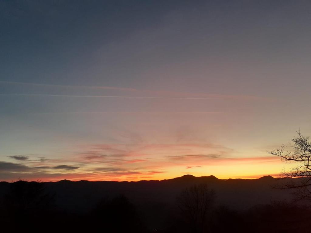 una puesta de sol con montañas en el fondo en Il Rifugio nel Comero, en Verghereto