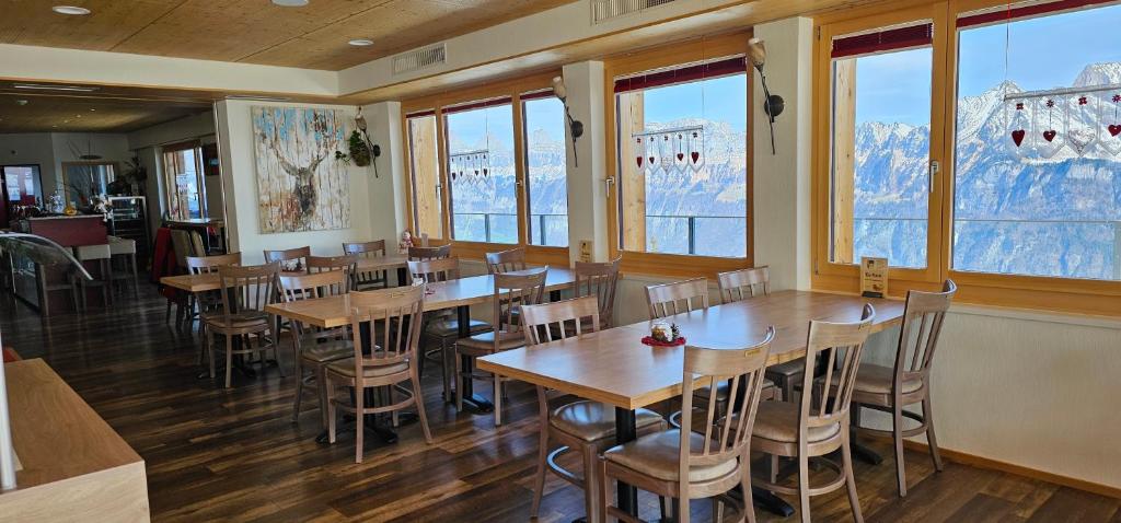 ein Restaurant mit Holztischen, Stühlen und Fenstern in der Unterkunft Berghotel Schonhalden in Flums