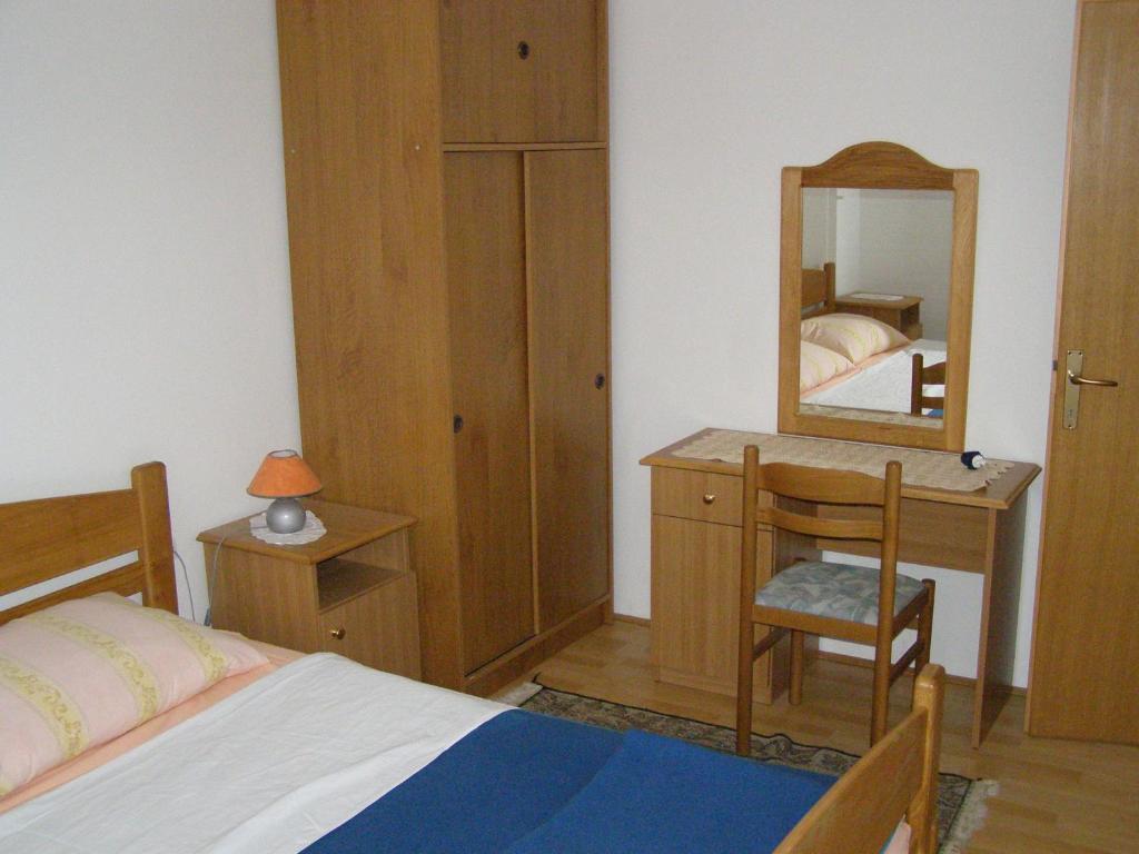 a bedroom with a bed and a dresser and a mirror at Apartments Kesic in Barbat na Rabu