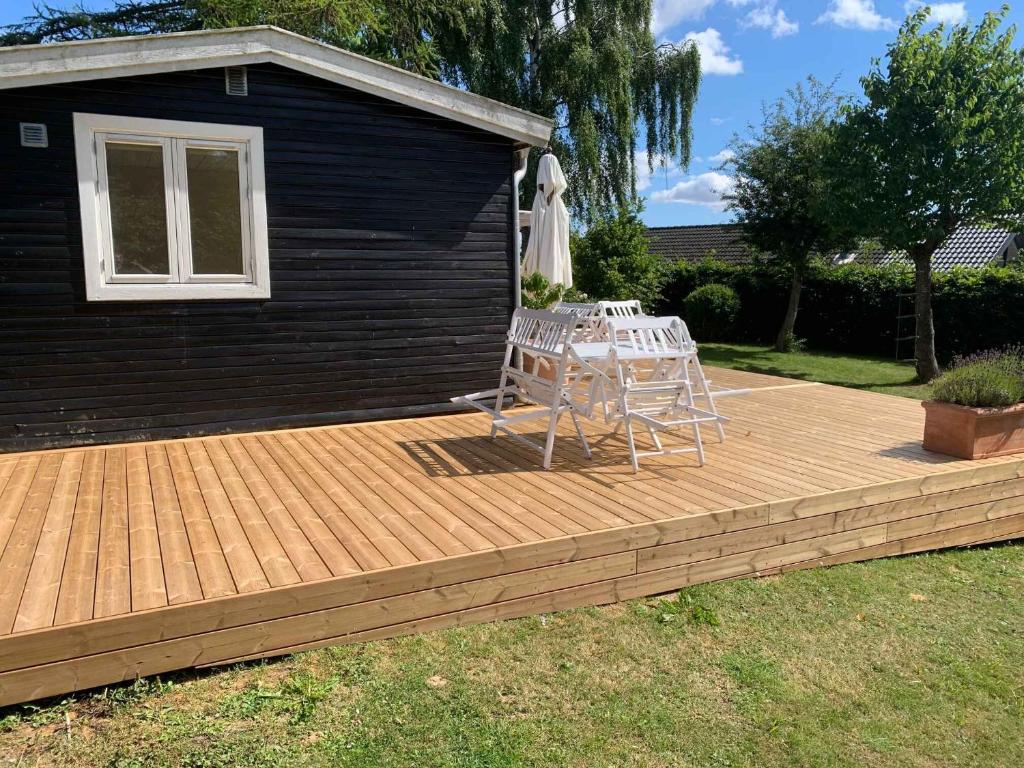 een houten terras met een tafel en een parasol bij Traditional Danish Summer House in Hornslet