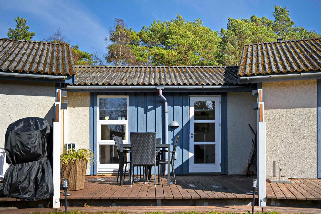 a house with a deck with a table and chairs at Holiday Apartment In Dueodde Holiday Park in Neksø