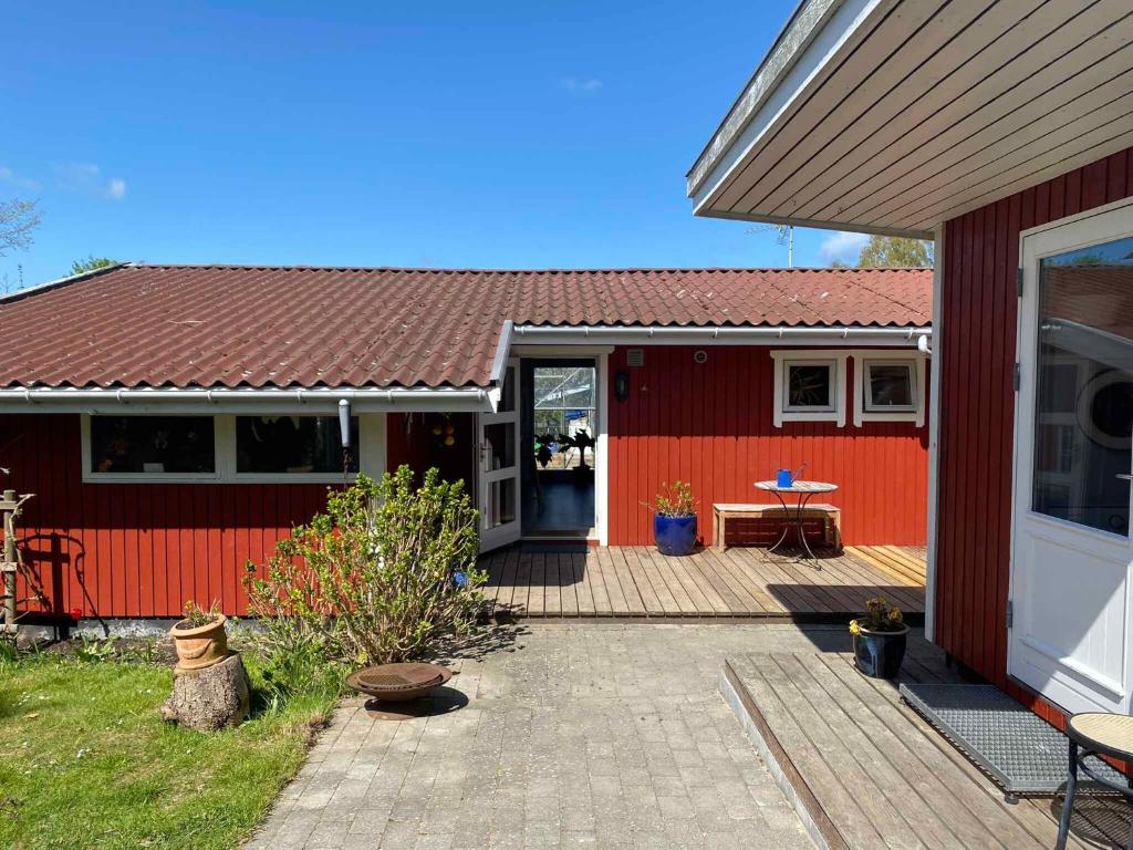 Casa roja con porche de madera y patio en Family Friendly Holiday Home In Or, en Holbæk