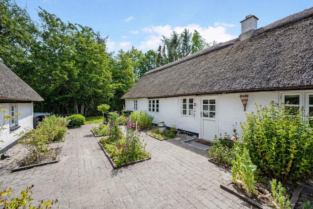 a garden in front of a white house with plants at Older Thatched Farmhouse, Approx, 400 Meters From The Water in Ørsted