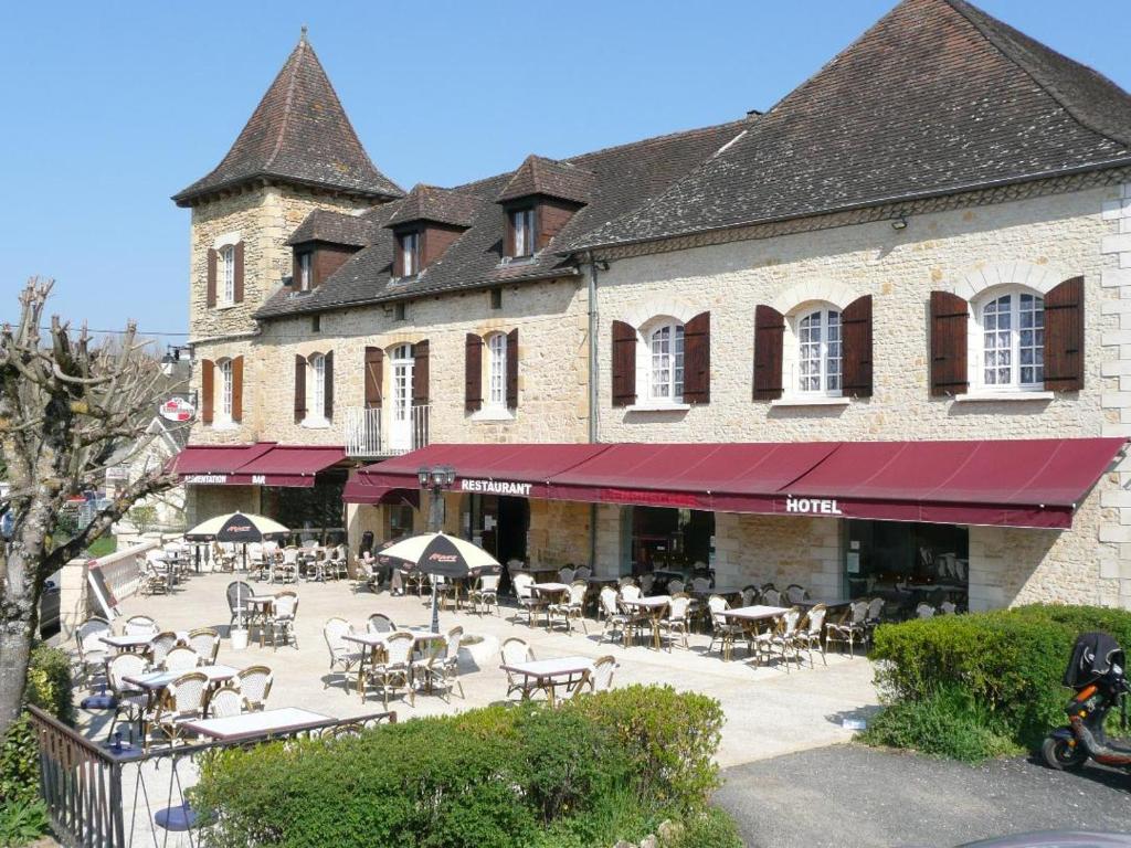 a building with tables and chairs in front of it at Hotel Restaurant L'Escale in Sainte-Nathalène