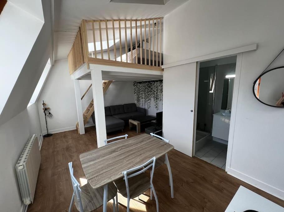 a living room with a table and a staircase at Le Lyautey - Appart neuf centre-ville Châteaudun in Châteaudun