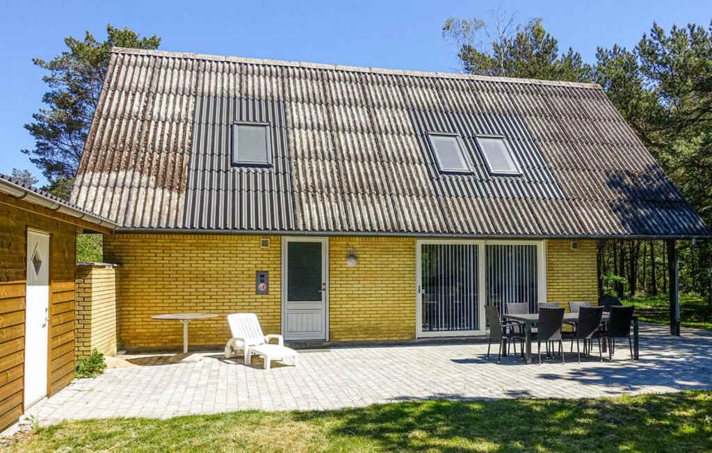 a yellow brick house with a table and chairs at Balkalyngen in Neksø