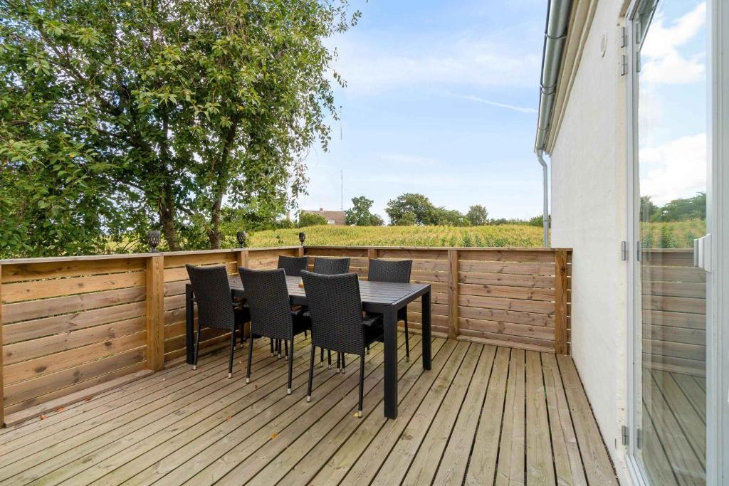 a wooden deck with a table and chairs on it at A Lovely Holiday Home In Quiet, Scenic Surroundings in Rønne