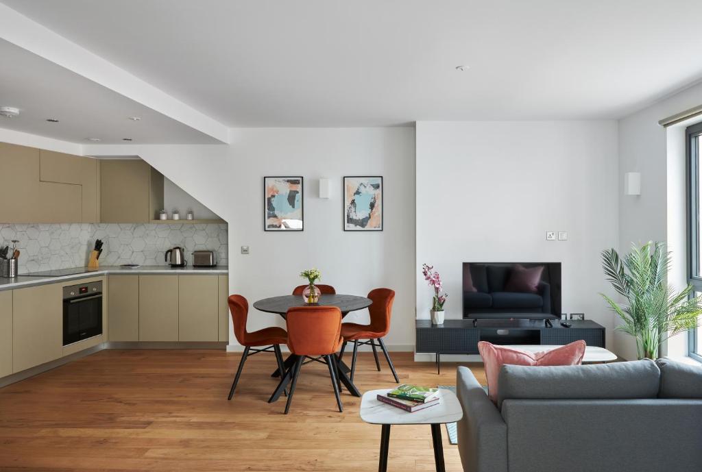 a kitchen and living room with a table and chairs at Hammersmith Mews by Viridian Apartments in London