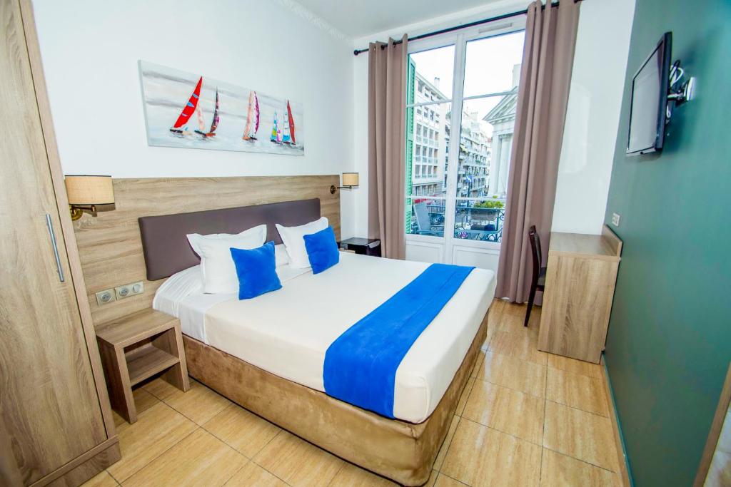 ニースにあるHôtel Parisienのベッドルーム1室(青い枕のベッド1台、窓付)