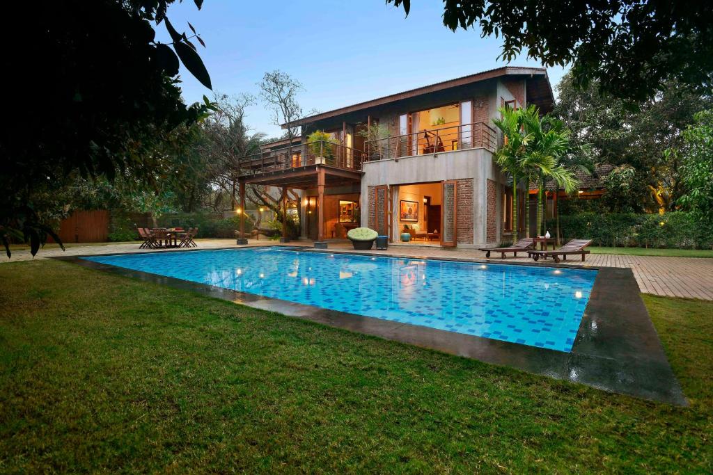 uma casa com piscina em frente a uma casa em ama Stays & Trails The Mango House, Alibag em Alibag