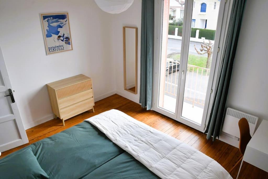 um quarto com uma cama e uma grande janela em Vue Pyrénéenne Élégante avec 2 chambres em Tarbes