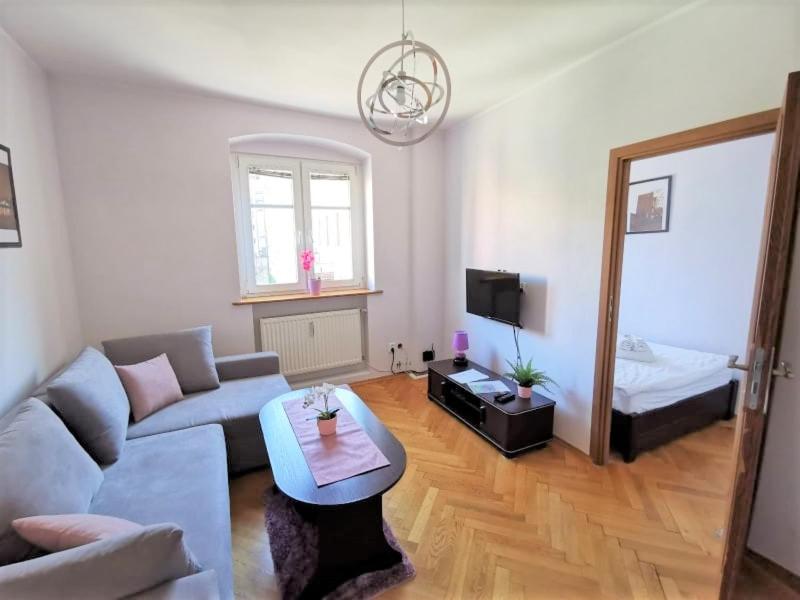 sala de estar con sofá, mesa y cama en Apartamenty Copernicus - zameldowanie 24 h en Toruń