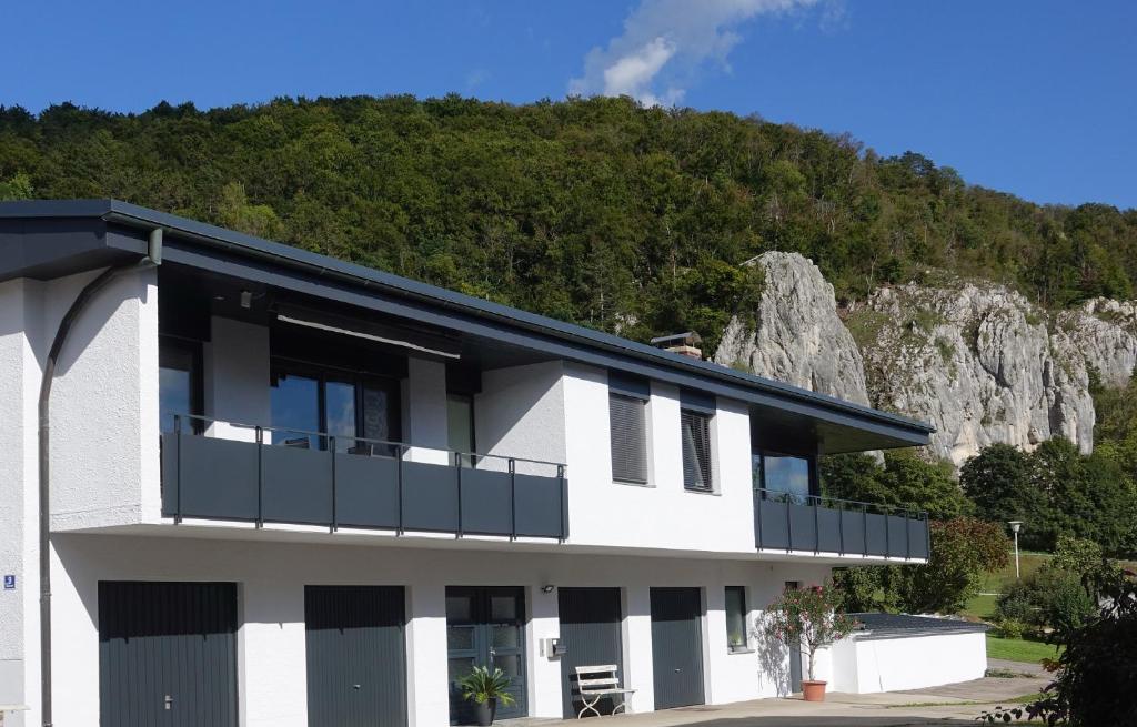 a white building with a balcony with a mountain in the background at Fewo Lehner in Riedenburg