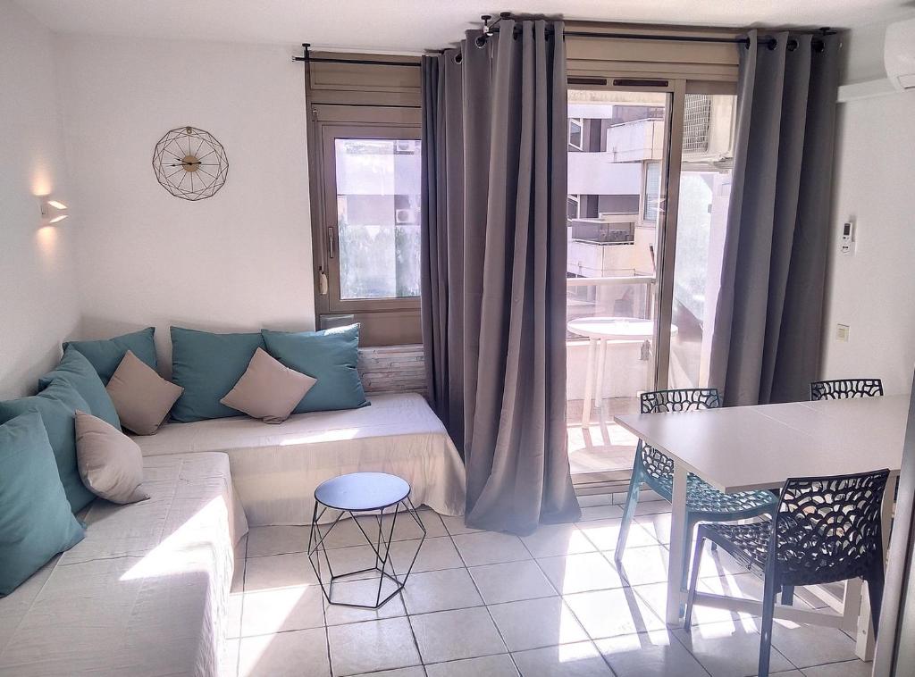 ein Wohnzimmer mit einem Sofa, einem Tisch und einem Fenster in der Unterkunft Résidence Graziella Studio 306 in Juan-les-Pins