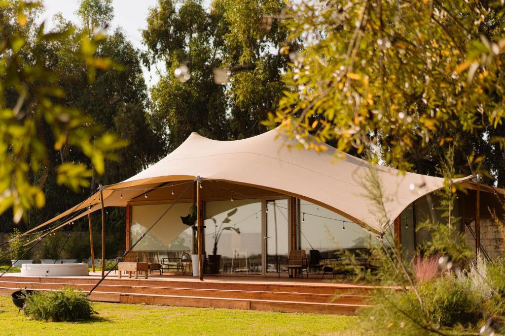 a tent in a field with trees in the background at Nabi Resort Glamping & SPA in Castel Volturno