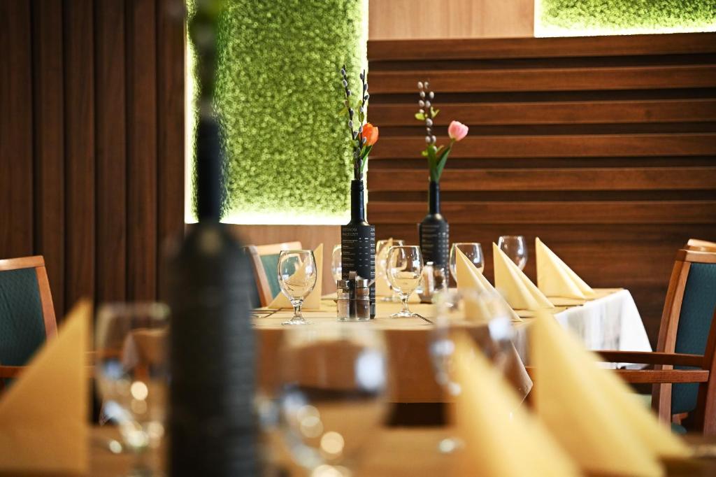 een tafel met glazen en bloemen in vazen erop bij Panorama Hotel Noszvaj in Noszvaj