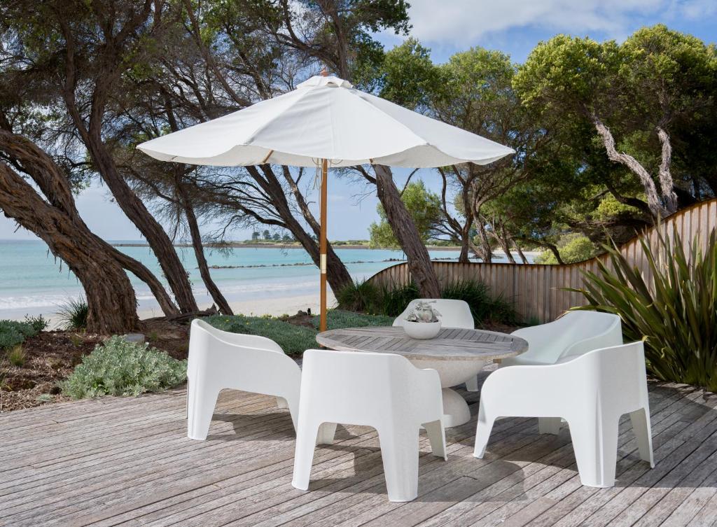 a table and chairs and an umbrella on a deck at The Cove Beach Front Luxury House in Port Fairy