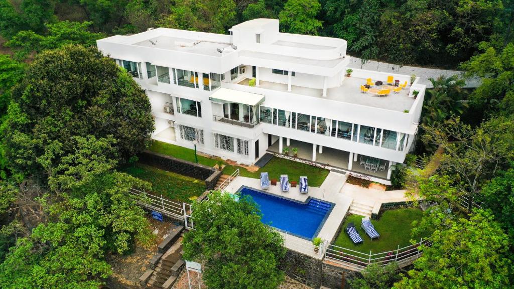 einen Luftblick auf ein großes weißes Haus mit einem Pool in der Unterkunft ama Stays & Trails White House, Lonavala in Lonavla