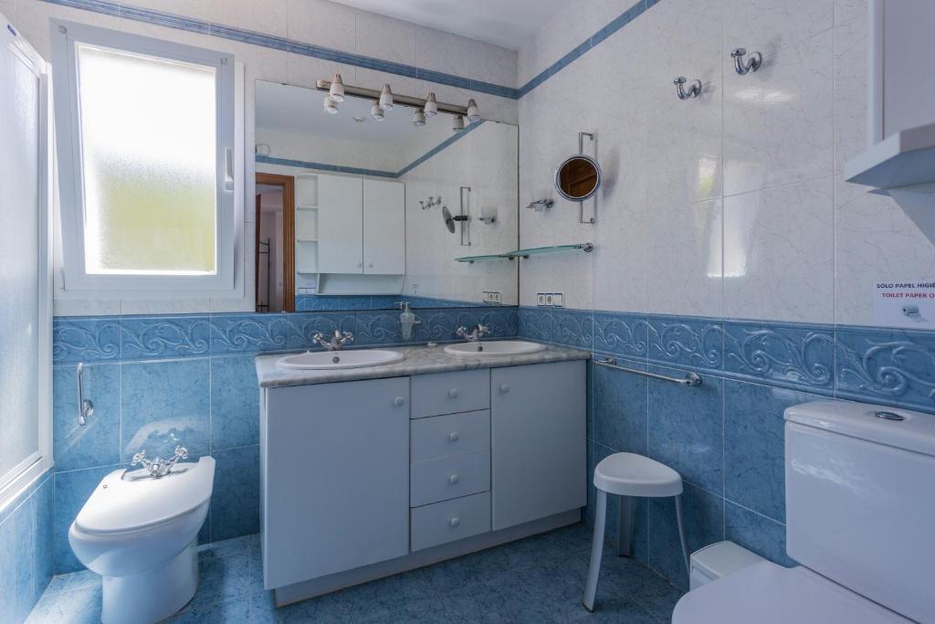 łazienka z 2 umywalkami, toaletą i oknem w obiekcie Villa S'illot 105 By MENORCARENTALS w Son Bou
