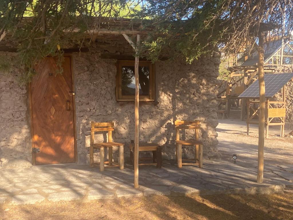a house with two chairs and a wooden door at El Huarango Eco retreat in La Huaica