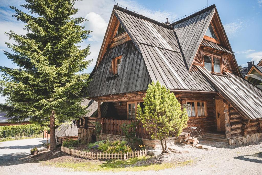 a large wooden house with a tree in front of it at Domki Javorina in Zakopane