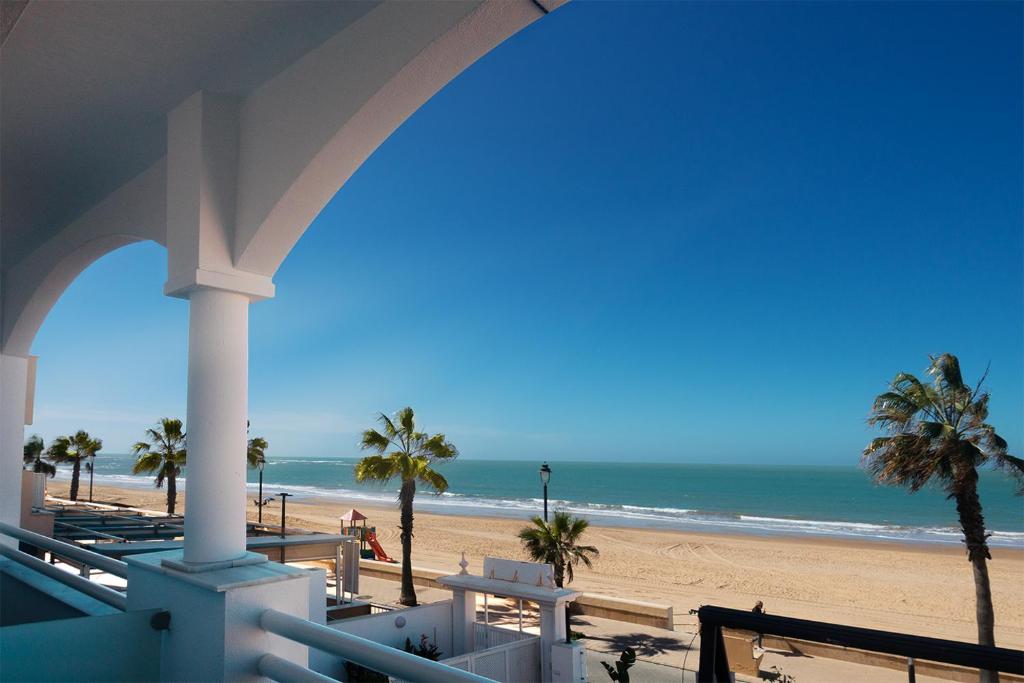 a view of the beach from the balcony of a resort at Hotel Vértice Chipiona Mar in Chipiona