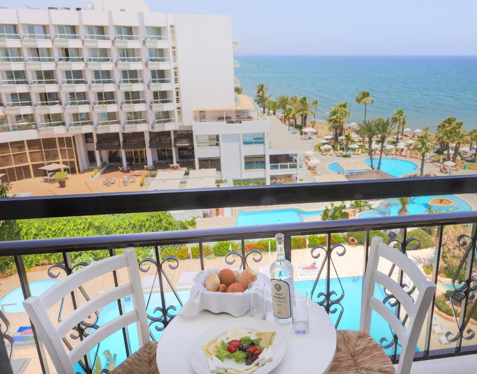 a table with food on a balcony with a view of the ocean at Sandy Beach Hotel & Spa - ex Sentido in Larnaca