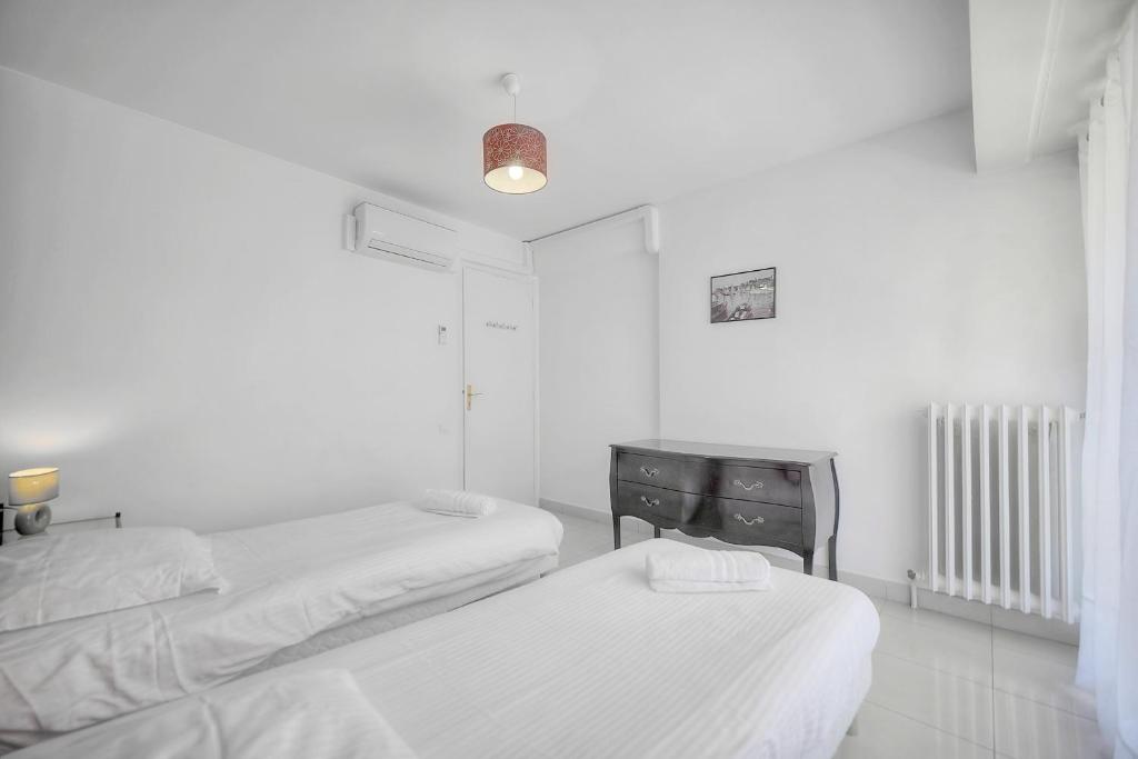 a white room with two beds and a radiator at IMMOGROOM - Renovated apartment - Terrace - AC in Cannes