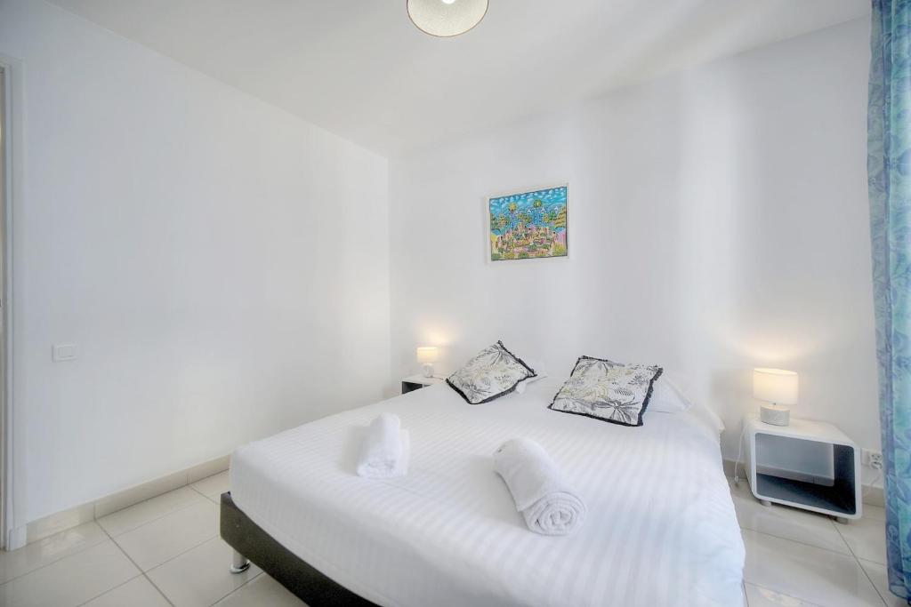 a white bedroom with a bed and a tv at IMMOGROOM - Renovated apartment - Terrace - AC in Cannes