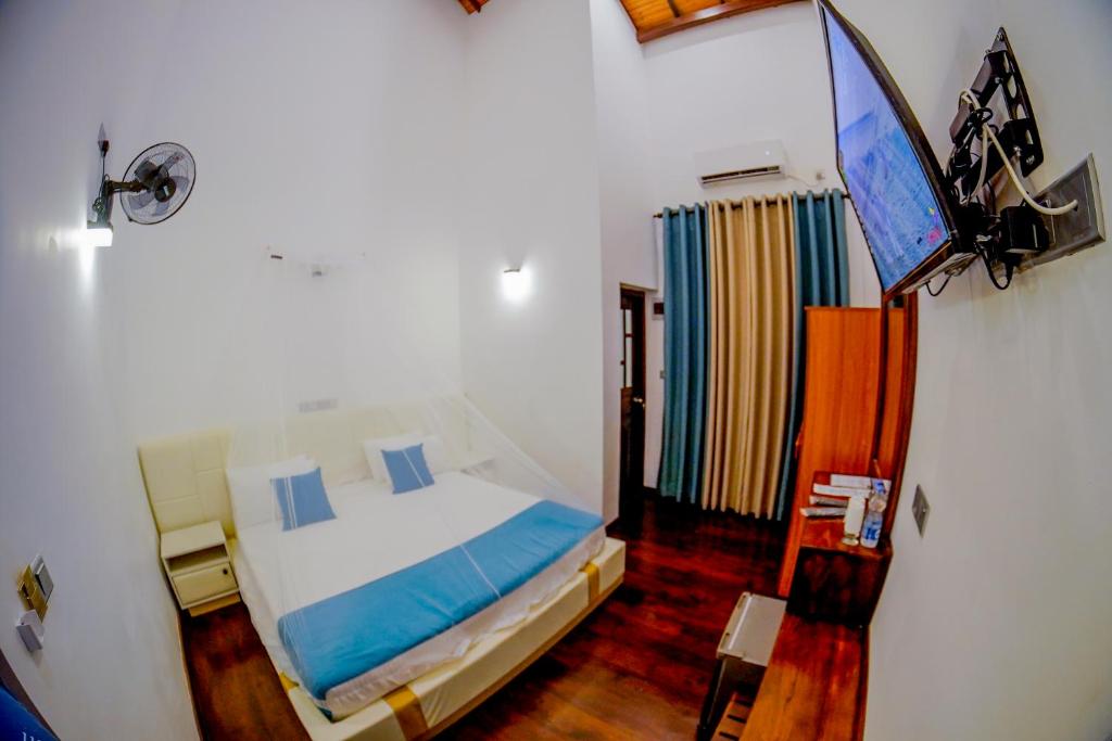 a bedroom with a bed and a flat screen tv at Even Beach Resort in Waikkal