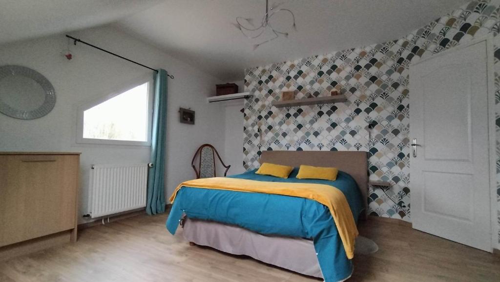 1 dormitorio con 1 cama con manta amarilla y azul en Appartement Vallée de la Risle, en Glos-sur-Risle