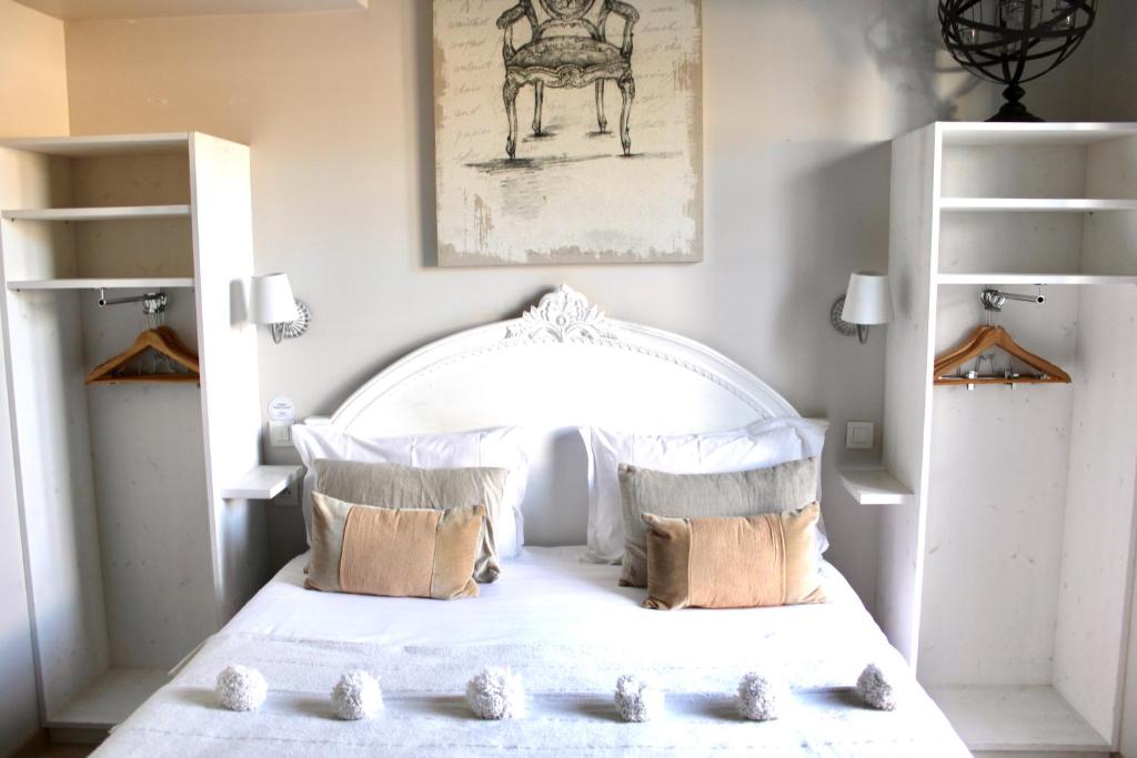 ein Schlafzimmer mit einem weißen Bett mit Kissen in der Unterkunft Fleur de Ré in Loix