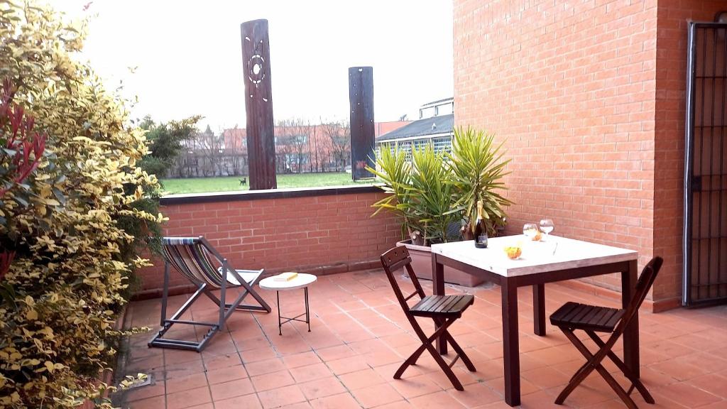 un patio con tavolo, sedie e muro di mattoni di Parco della danza a Reggio Emilia