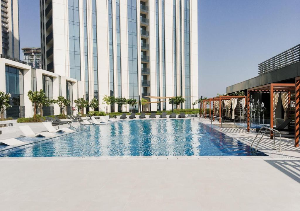 uma grande piscina com cadeiras e um edifício em Nasma Luxury Stays - Harbour Gate Tower 1 em Dubai