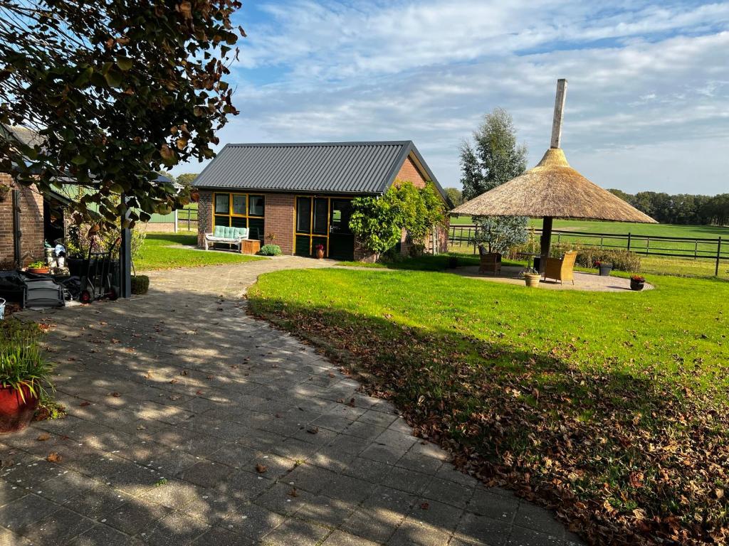 une petite maison avec un toit de paille et une cour herbeuse dans l'établissement Gastenverblijf De Handwijzer, à Hengelo