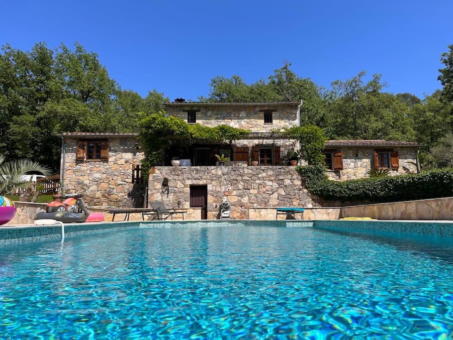 una grande piscina di fronte a una casa di Magnifique villa en pierre au calme absolu a Fayence