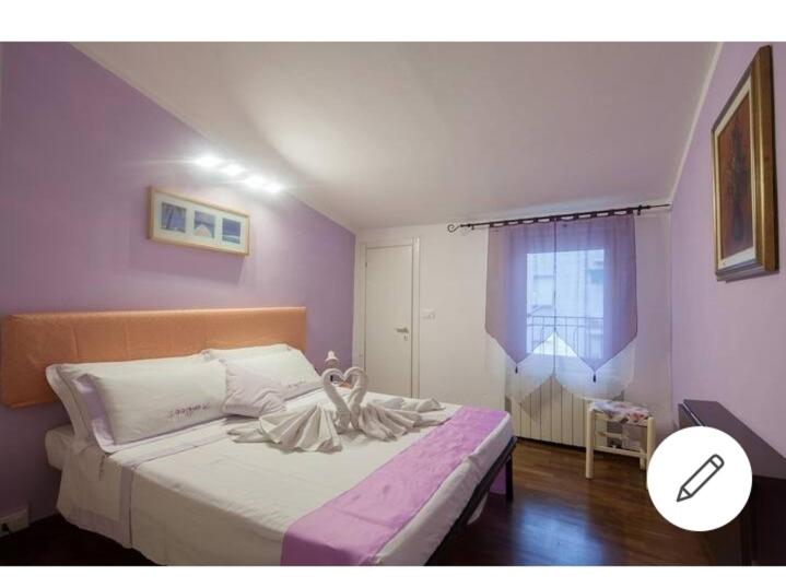 um quarto com uma cama com uma parede roxa em Affittacamere La Mansarda del Centro em La Spezia