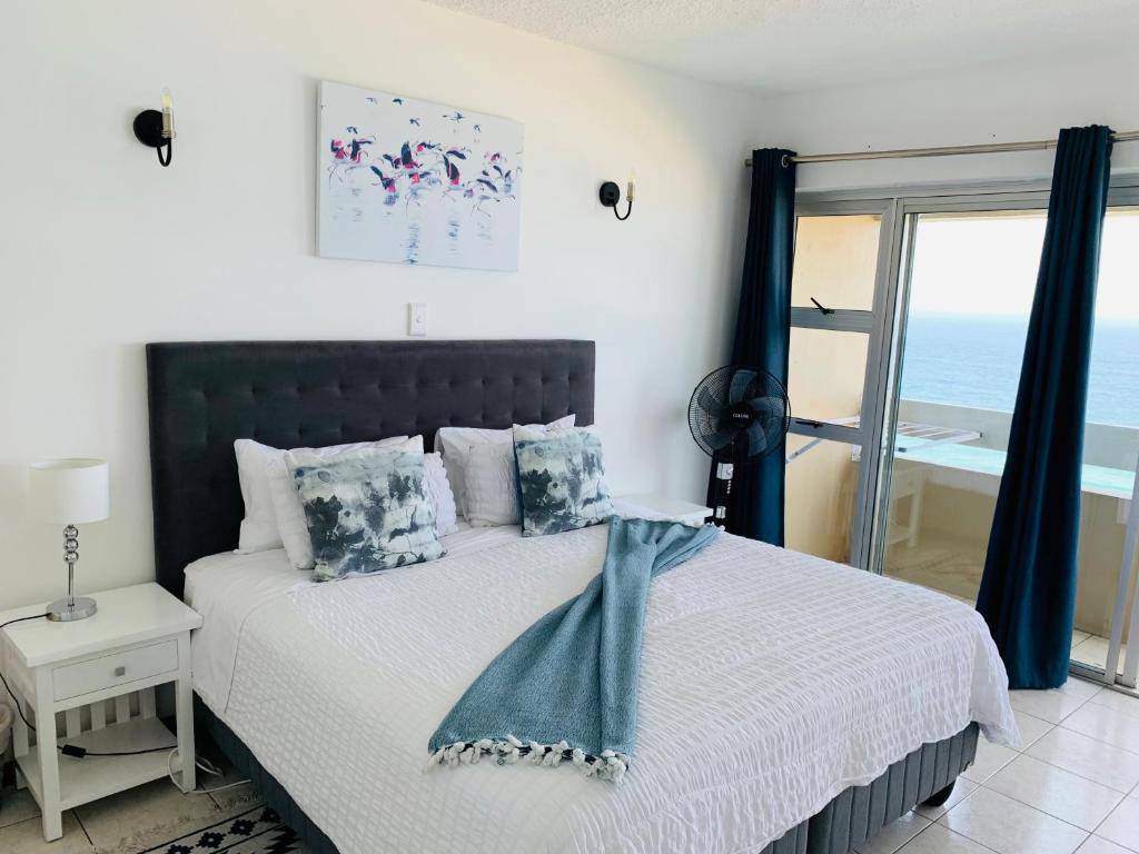 a bedroom with a bed with a view of the ocean at Serene Seascape Apartments in Amanzimtoti