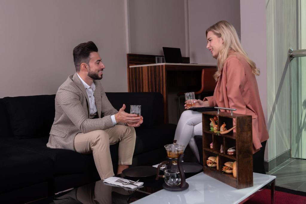 a man and woman sitting on a couch holding wine glasses at Centro Al Manhal by Rotana in Abu Dhabi