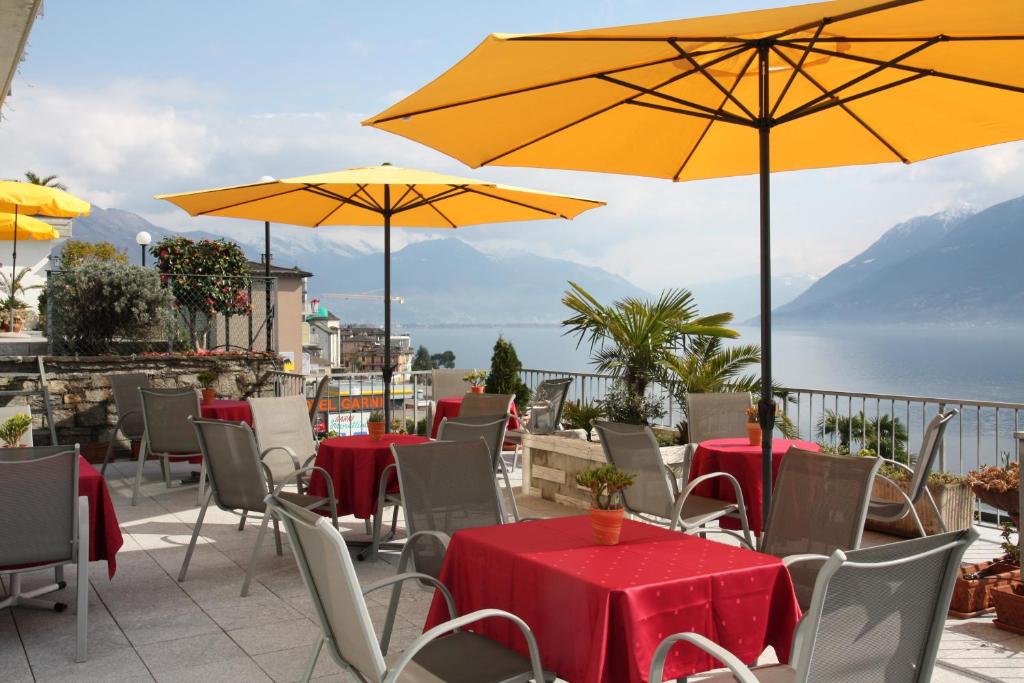 eine Terrasse mit Tischen, Stühlen und gelben Sonnenschirmen in der Unterkunft Hotel Garni Morettina in Brissago