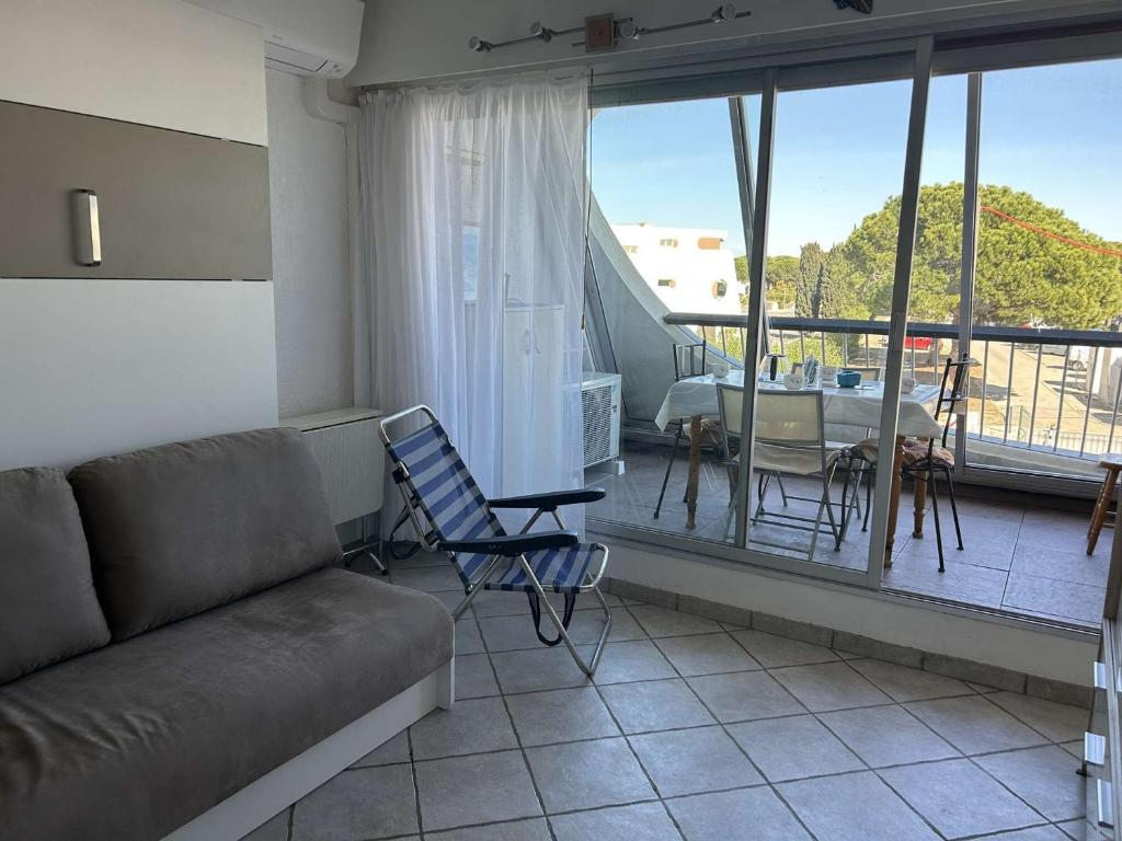 d'un salon avec un canapé et une table ainsi que d'un balcon. dans l'établissement Studio Cabine Climatisé, Plage et Piscine, 4 Couchages - Port Camargue - FR-1-250-151, au Grau-du-Roi