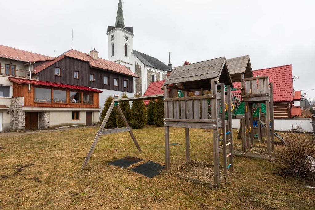 a group of playground equipment in a yard with a church at Chata u kostela in Kořenov